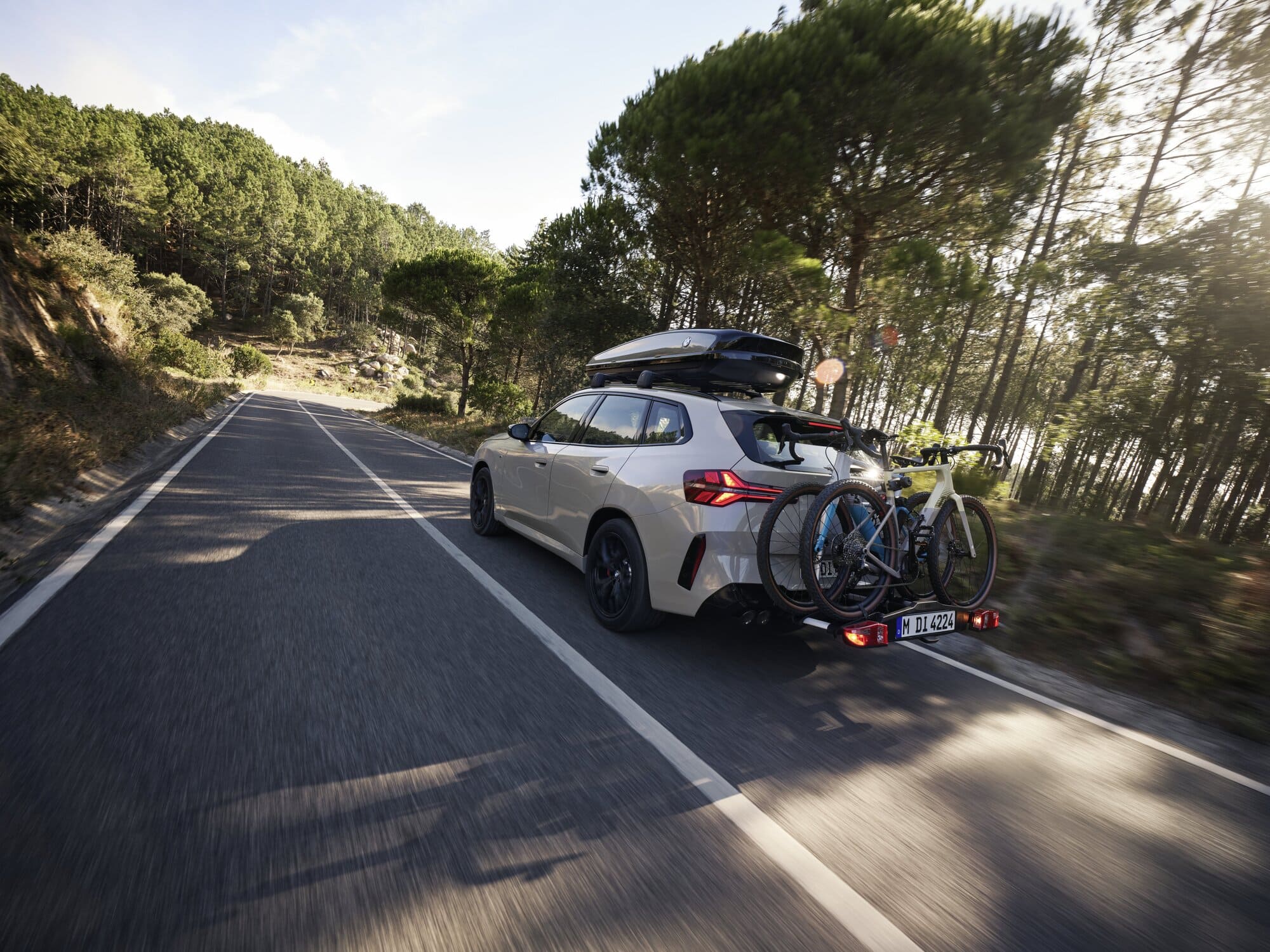 BMW X3 mit Dachgepäckbox und Radträger auf einer Straße