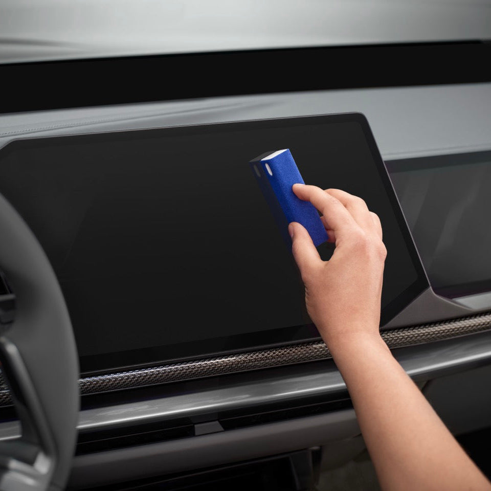 Blauer Displayreiniger wird eingesetzt um ein Display im Fahrzeug zu reinigen