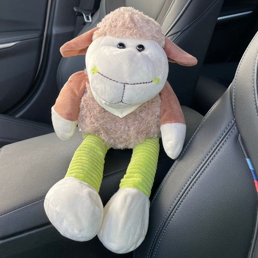Kuscheltier Schaf Helmine ist braun mit grünen Cordbeinen und sitzt auf der Armablage in einem Auto.