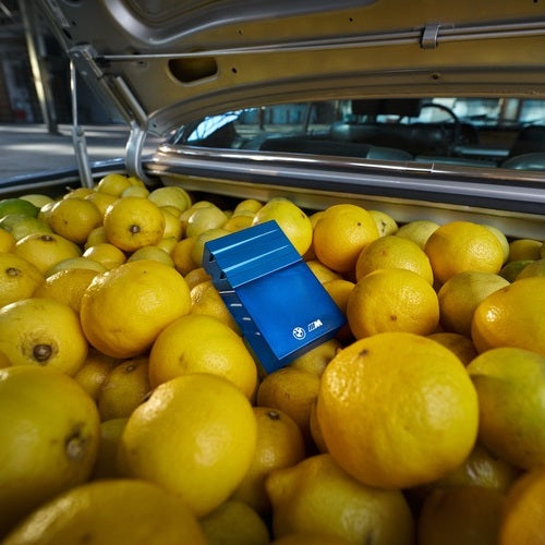 BMW Parfüm "1972" Flacon liegend in einem Motorraum voller gelber Zitronen