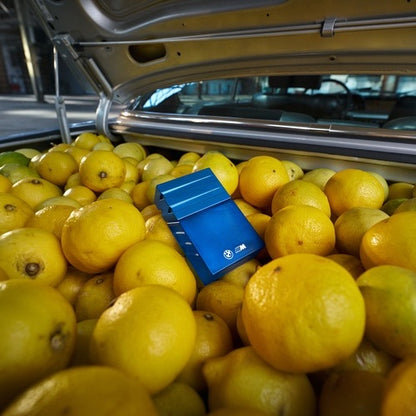 BMW Parfüm "1972" Flacon liegend in einem Motorraum voller gelber Zitronen