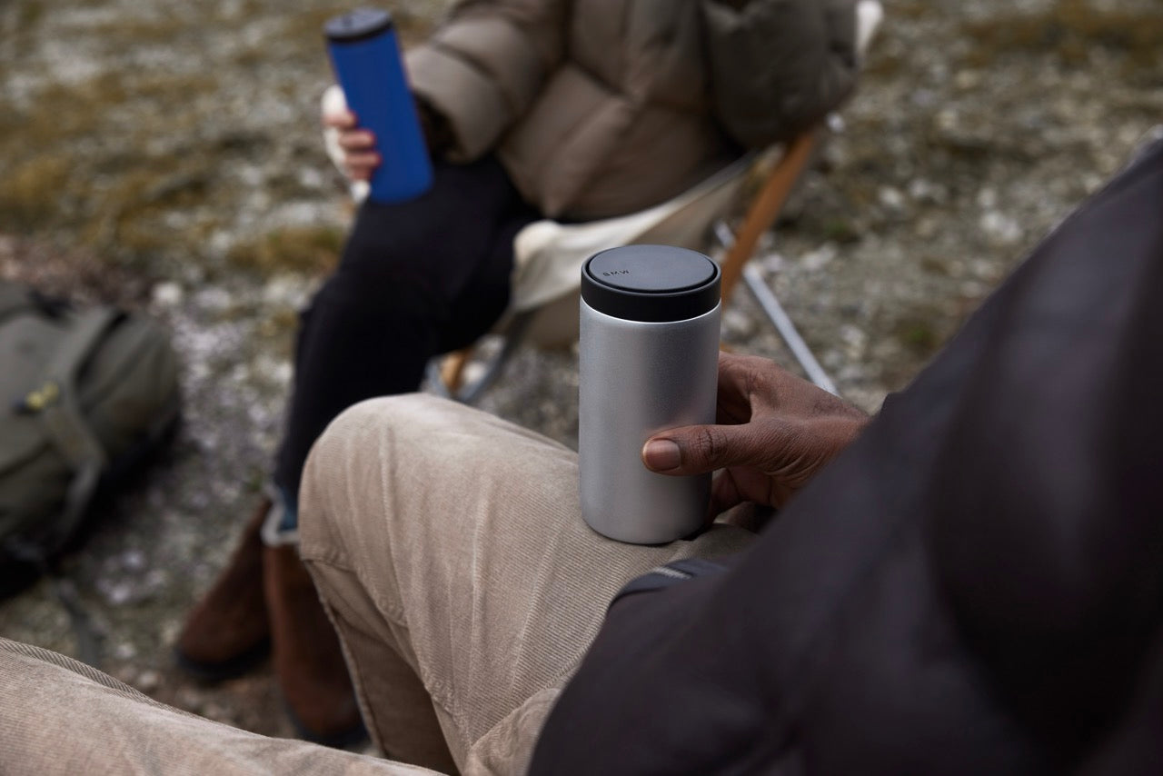 silberner Thermobecher in der Hand